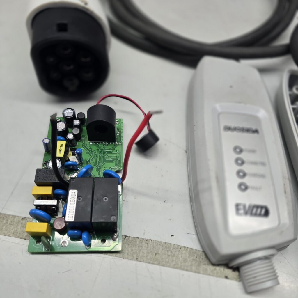 Portable EV charger control board out of its enclosure beside the charging cable and plug